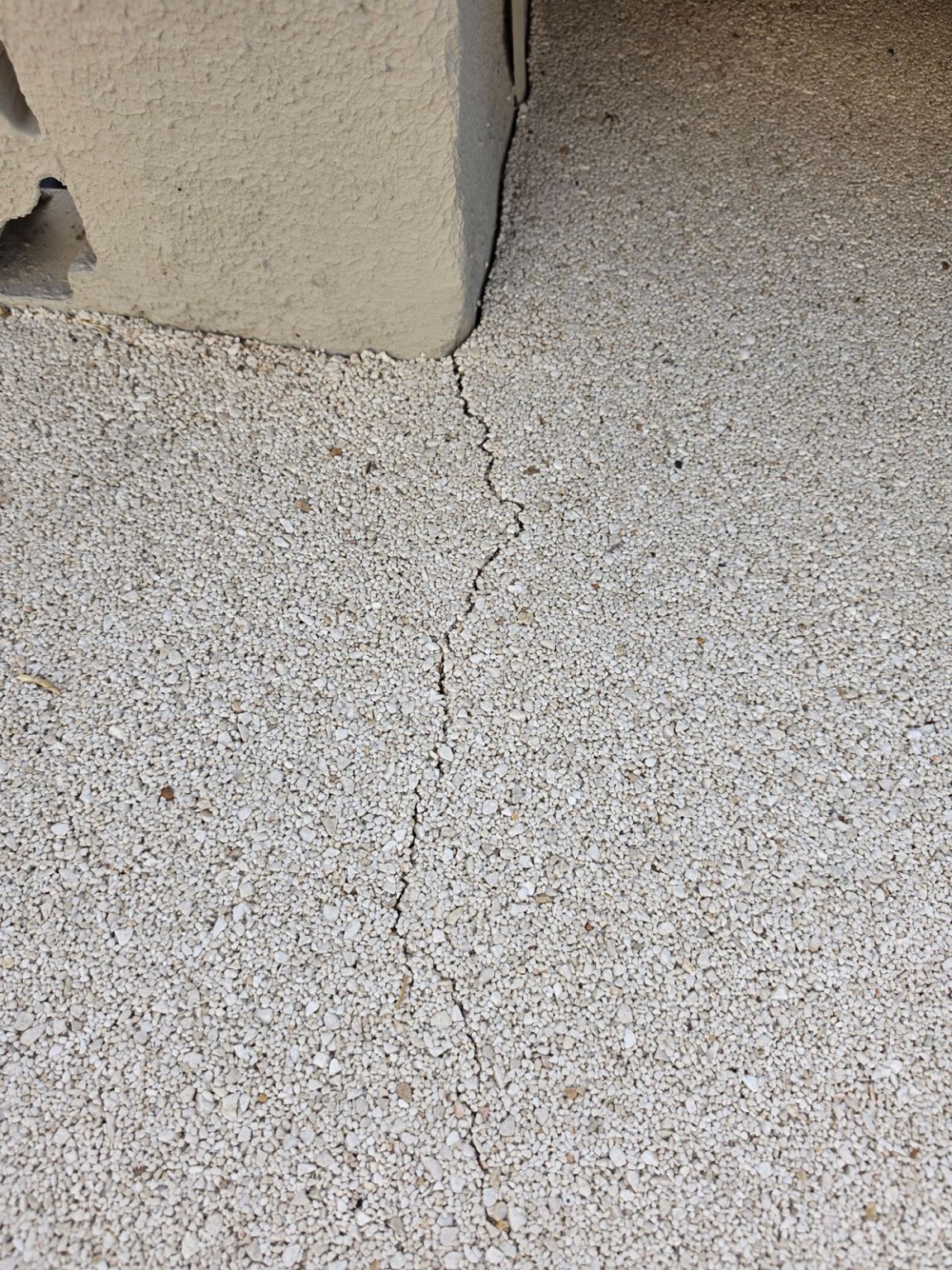 Crack running through a resin bound surface beside a wall